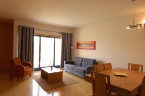 a living room with a blue couch and a table at Orada Apartamentos Turísticos - Marina de Albufeira in Albufeira