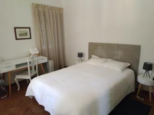 um quarto com uma grande cama branca e uma secretária em Penaferrim Sintra Rooms em Sintra