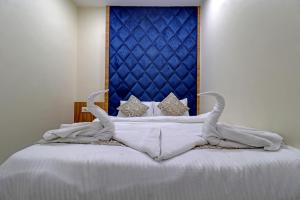 1 cama con sábanas blancas y cabecero azul en Ivory Suites, en Airoli