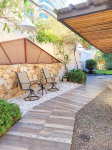 un patio con 2 sillas y una pared de piedra en "Casa Amalia Apartamentos" Ubicación Privilegiada con Jardín en Mendoza