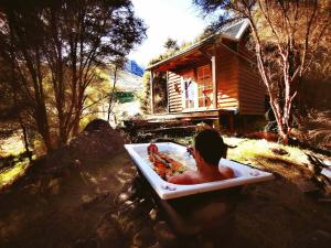a person in a bath tub with a slice of pizza at Manaaki Mai, Rustic Retreat Bush Cabin in Christchurch