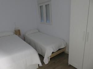 2 łóżka w białym pokoju z oknem w obiekcie Belice, excepcional apartamento con Jacuzzi w mieście Punta Umbría