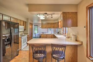 a kitchen with wooden cabinets and a island with bar stools at Serene Lakeside Hideaway with Deck in Downtown! in Lakeside