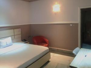 1 dormitorio con 1 cama y 1 silla roja en Haven Suites, Ikenegbu en Owerri