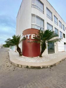 a building with palm trees in front of it at Pousada Ritec in Linhares