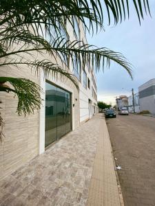 a building with a palm tree next to a street at Pousada Ritec in Linhares