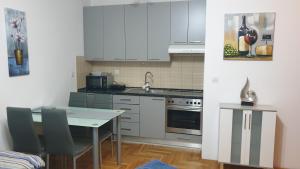 una cucina con armadi bianchi e tavolo con sedie di Apartman MM012 a Požarevac