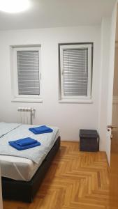 a bedroom with a bed and two windows at Apartman MM012 in Požarevac