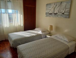 two beds in a hotel room with a painting on the wall at Sea View Apartment in Faro