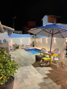 patio con tavolo e ombrellone accanto alla piscina di BOA SORTE SUITES com PISCINA, GARAGEM e Pé na PRAIA de GERIBÁ a Búzios