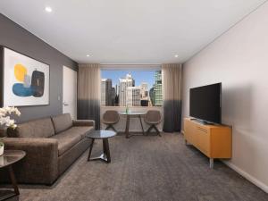 a living room with a couch and a flat screen tv at Novotel Sydney Darling Harbour in Sydney