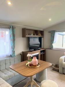 a living room with a table and a couch at Lovely 3 bedroom holiday home in Seton Sand caravan park Wi-Fi Xbox in Edinburgh