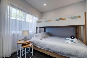 a bedroom with a bunk bed and a table with a lamp at Classic Contemporary Beach Beauty in Inverloch