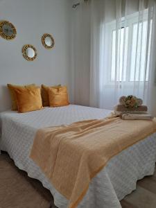 1 dormitorio con 1 cama blanca grande con almohadas de color naranja en CASA VAGOS, en Nazaré