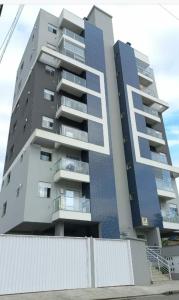 un edificio de apartamentos alto con una valla blanca delante de él en Agradável apartamento em bairro silencioso..., en Camboriú