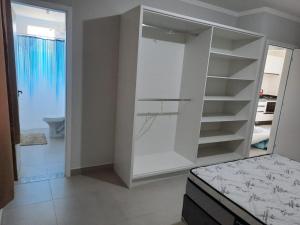 Armario blanco en una habitación con baño en Agradável apartamento em bairro silencioso..., en Camboriú