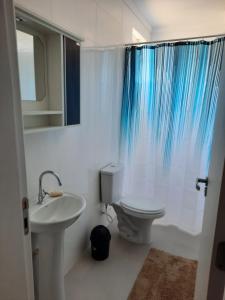 Baño blanco con aseo y lavamanos en Agradável apartamento em bairro silencioso..., en Camboriú