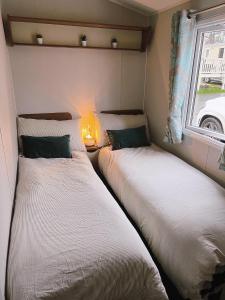 two beds in a small room with a window at Lovely 3 bedroom holiday home in Seton Sand caravan park Wi-Fi Xbox in Edinburgh
