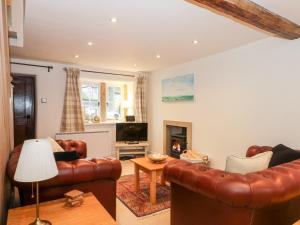 a living room with leather furniture and a fireplace at Dragon Cottage in Bakewell