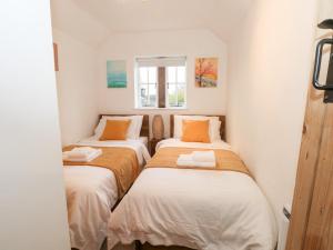 two beds in a small room with white walls at Dragon Cottage in Bakewell