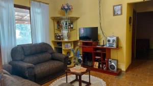 een woonkamer met een bank, een stoel en een televisie bij Recanto Magalhães in São Bento do Sapucaí