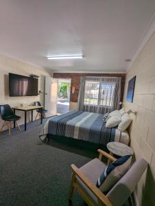a hotel room with a bed and a table and chairs at Sail Inn Motel in Yeppoon