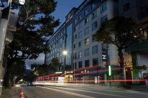 Una calle de la ciudad con un edificio y una farola. en Hotel Zinc, en Seogwipo