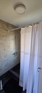baño con ducha con cortinas blancas en Kuntur Apart en El Chaltén