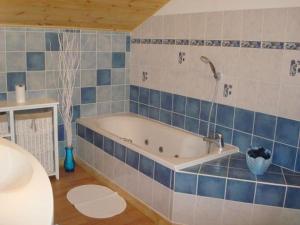 a bath tub in a bathroom with blue tiles at Chalet haut de gamme avec sauna, terrasse et jardin près de la montagne vosgienne - FR-1-589-185 in Saint-Nabord +27 photos