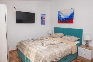 Schlafzimmer mit einem Bett und einem Flachbild-TV in der Unterkunft Family friendly house with a swimming pool Cista Velika, Vodice - 20227 in Velika Čista