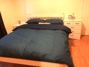 sypialnia z łóżkiem z niebieską pościelą i komodą w obiekcie Private room in Highgate London w Londynie