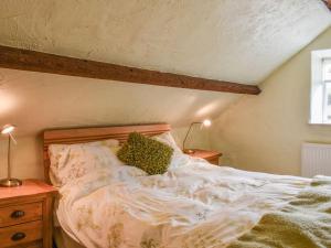 an unmade bed in a bedroom with two lamps at The Loft - Ukc6139 in Cartmel