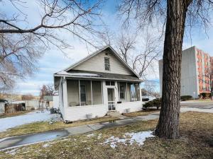 uma pequena casa branca com uma árvore ao lado em Cozy cottage in the heart of the big city- dog friendly em Billings