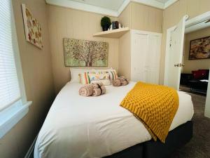 a bedroom with a large white bed with a yellow blanket at Cozy cottage in the heart of the big city- dog friendly in Billings