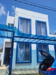 una casa azul y blanca con un coche aparcado delante en Casa Vacacional en Carmen de Apicala, Colombia, en Carmen de Apicalá