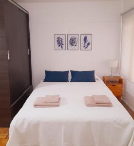 um quarto com uma cama branca com duas toalhas em Mendoza Apartment em Mendoza