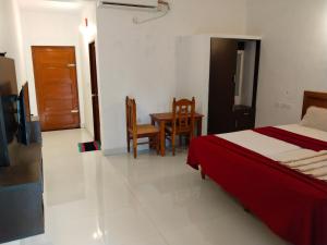 a bedroom with a bed and a table and chairs at Hotel Neptune Kovalam in Trivandrum