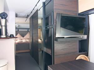 a small room with a tv and a bedroom at Dreamer luxury caravan on the backwaters, Lütow in Lütow