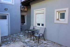 a patio with chairs and a table and a wall at Apartmani 15 in Cetinje