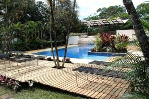 una piscina con terraza de madera junto a una casa en Glamping bali, en Sopetrán