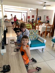 three young boys sitting at a table in a restaurant at Pousada Moça Bonita in Ubatuba