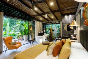 a bedroom with a large bed and a living room at awā Beachfront Hotel in Puerto Viejo