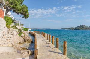 a wooden fence next to the water with a beach at House Hidden Beauty in Tribunj