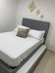 1 cama con sábanas blancas y almohadas en una habitación en Apartment near to Bello Horizonte Beach, en Santa Marta