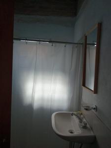 uma casa de banho com uma cortina de chuveiro branca e um lavatório. em Madrenatura em Mina Clavero
