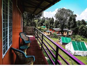 a porch of a house with chairs on it at Chopta Eco Cottage & Camping in Sari