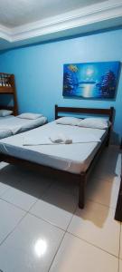 two beds in a room with a blue wall at Sol de Iracema centro in Fortaleza