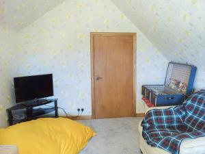 Habitación con cama, TV y puerta en Glen Rosa, en Dalrymple