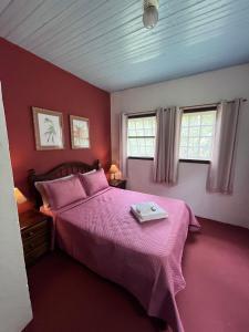 um quarto com uma cama rosa e 2 janelas em Chalé Gaia - Itatiaia em Itatiaia