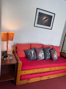 um sofá vermelho com almofadas num quarto em Chalé Gaia - Itatiaia em Itatiaia
